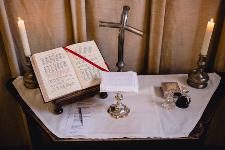 An open bible with two candles and crucifix on a table